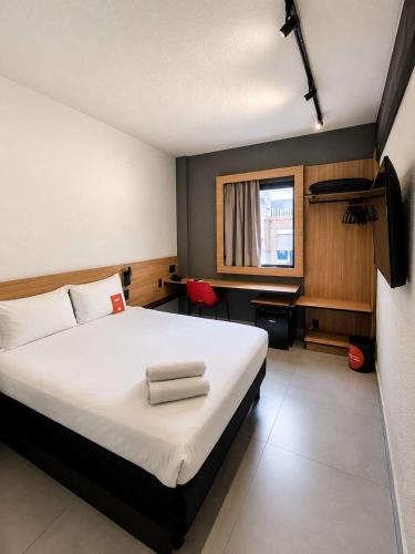 a bedroom with a large white bed with a window at ibis Santos Gonzaga Praia in Santos