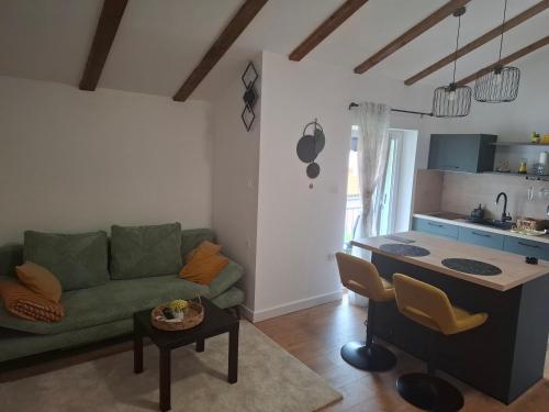 a living room with a green couch and a kitchen at Apartman Pojine in Gabonjin