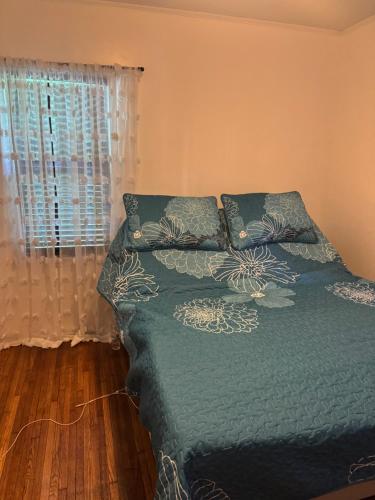 a bedroom with a bed with a green comforter and a window at Logans Lodge in Minneapolis