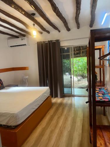 a bedroom with a bed and a wooden floor at One Love Garden Villas Paje in Kiganga