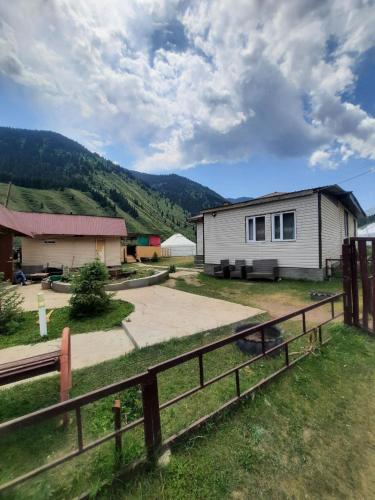 a house with a fence next to a building at Guest hous Aibek in Kurmenty