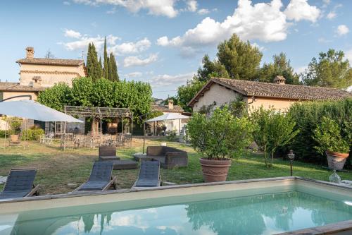 a pool in a yard with chairs and a house at Il Borgo delle Pampare in Campello sul Clitunno