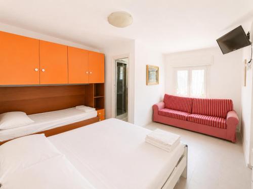 a room with two beds and a red couch at Anthea - Timavo apartment 2 in Lignano Sabbiadoro