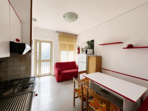 a kitchen with a table and a red couch at Anthea- Paluzza Apartment & Parking in Lignano Sabbiadoro