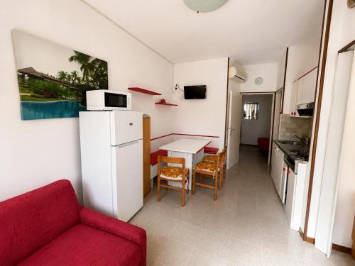 a living room with a red couch and a white refrigerator at Anthea- Paluzza Apartment & Parking in Lignano Sabbiadoro