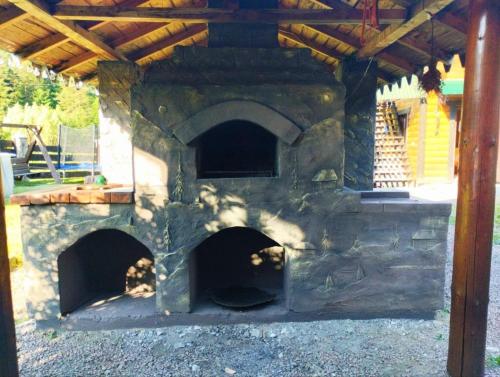 an outdoor brick oven with a wooden roof at Шум лісу in Tatariv