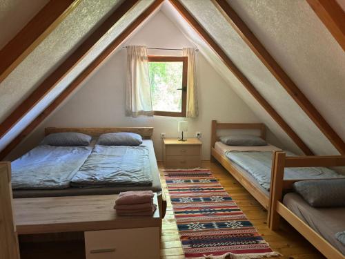 a attic bedroom with two beds and a window at Pure Nature in Bihać
