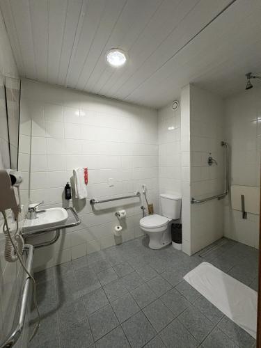 a bathroom with a toilet and a sink and a shower at ibis Santos Gonzaga Praia in Santos