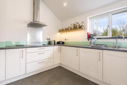 a kitchen with white cabinets and a window at Ty Top in Newport