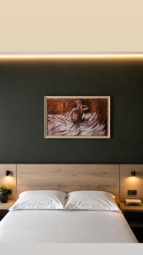 a bedroom with a bed with a painting on the wall at Hotel Idi in Vlorë
