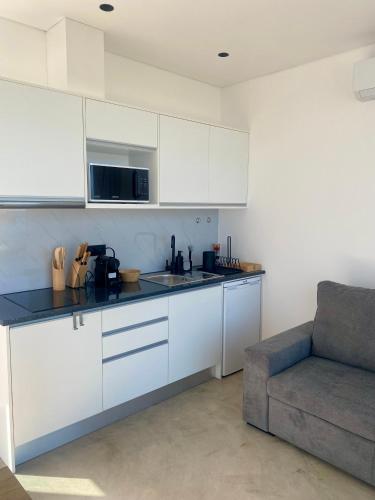 a kitchen with white cabinets and a couch at Riba D'Mar - B in Machico