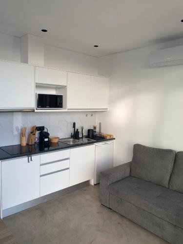 a kitchen with white cabinets and a couch in a room at Riba D'Mar - B in Machico
