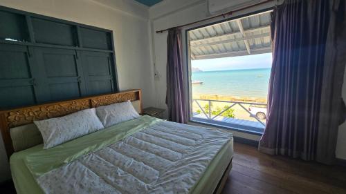 a bedroom with a bed with a view of the ocean at Bamboo Khiri in Sathani Rot Fai