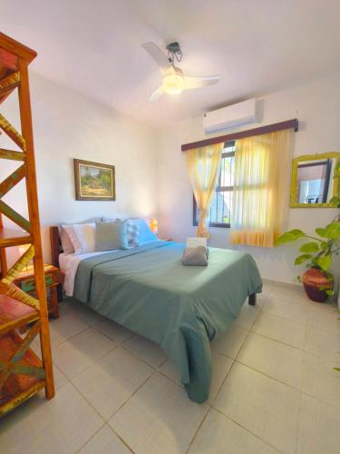 a bedroom with a bed with a green comforter at Quinta essência suites e chalés in Ubatuba