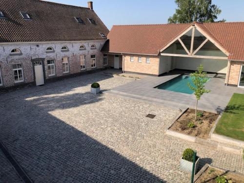 a large courtyard with a house and a swimming pool at Hof Ten Beemd in Oudenaarde