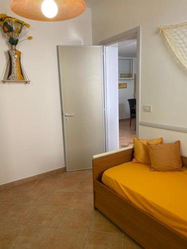 a bedroom with a bed with yellow sheets and a closet at Romano Holiday 3 in Marina di Pescoluse