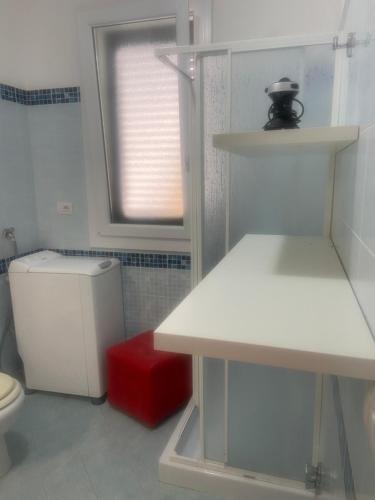 a white bathroom with a toilet and a window at Romano Holiday 3 in Marina di Pescoluse