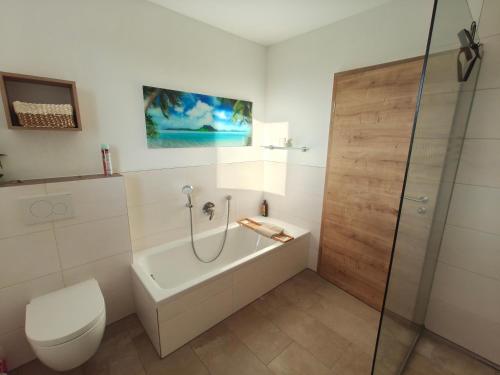 a bathroom with a tub and a toilet and a shower at Morgenrot Panorama Apartment 1 - Terrasse in Gnotzheim