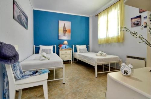 a blue room with two beds and a chair at Alessandro's Apartment in Mantoúkion