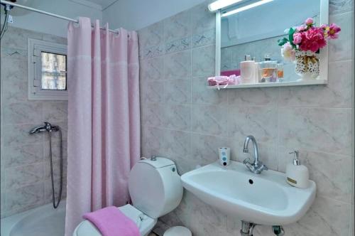 a bathroom with a pink shower curtain and a toilet and sink at Alessandro's Apartment in Mantoúkion