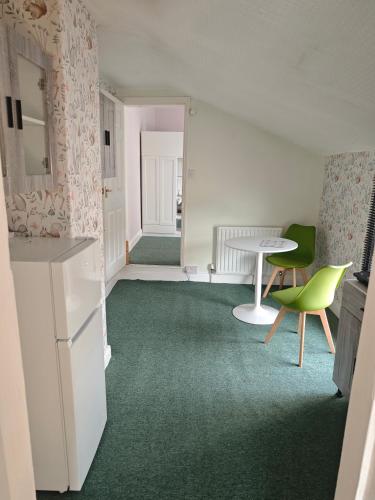 a room with a table and a green chair at St Peters Avenue in Cleethorpes