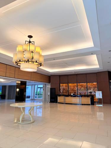 a large lobby with a table and a chandelier at Shell Residences MOA by Jersey in Manila