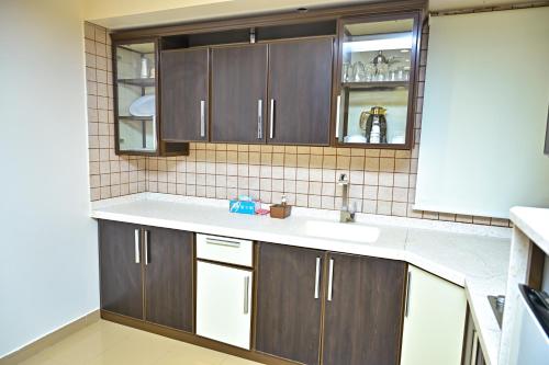 a kitchen with brown cabinets and a sink at تارا للشقق المخدومة in Riyadh