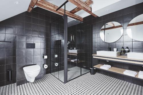 a bathroom with a toilet and two sinks and mirrors at Havn Hotell og Restaurant in Skudeneshavn