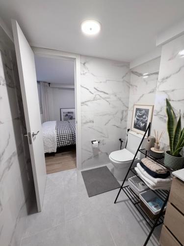 a white bathroom with a toilet and a bedroom at Blue rooms in Bilbao
