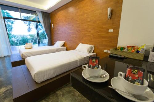 a hotel room with two beds and two cups of tea at Pagoda Sight Residence in Nan