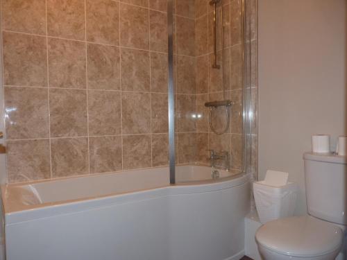 a bathroom with a tub and a toilet and a shower at The Old Seven Stars in Okehampton