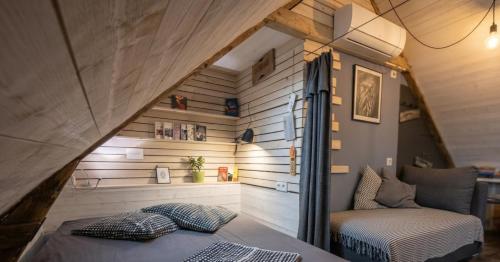 an attic bedroom with a bed and a couch at Le Loft de l'auberge du Lac Noir in Saint-Cernin-de-Larche