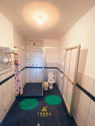 a bathroom with a toilet and green mats on the floor at Terra House Hostel in Cusco