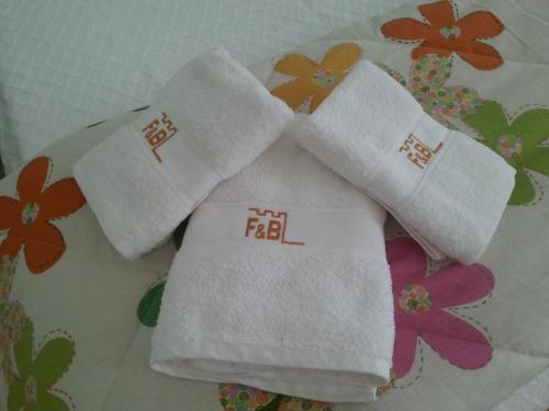 three white towels sitting on top of a table at Alojamento Local F&B in Guimarães