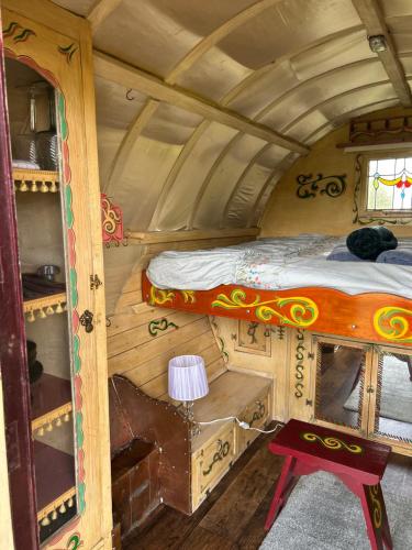 a small room with a bed and a table in it at Vardo gypsy wagon in Berwick Saint John