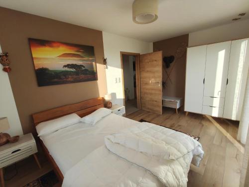 a bedroom with a white bed and a painting on the wall at Morgenrot Panorama Apartment 1 - Terrasse in Gnotzheim