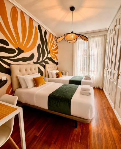 two beds in a room with a painting on the wall at Callao Suites in Madrid