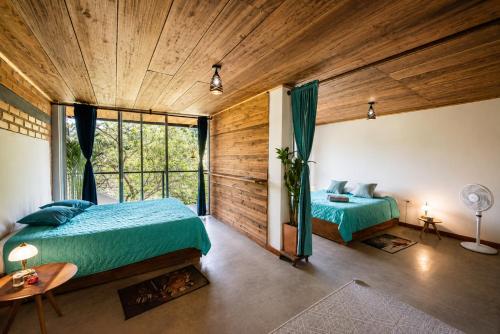 two beds in a room with wooden walls and windows at Pistacho in Minca