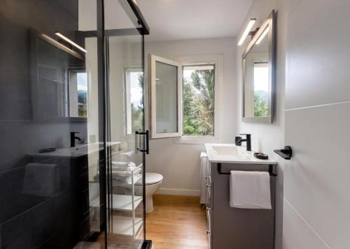 a bathroom with a sink and a toilet and windows at o fogar do cipres in Rivela
