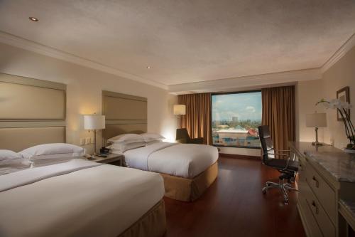 a hotel room with two beds and a window at Barcelo Guadalajara in Guadalajara