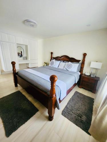 a bedroom with a large bed with a wooden frame at Jadens Guest House - by ZenBreak in Saint Michael