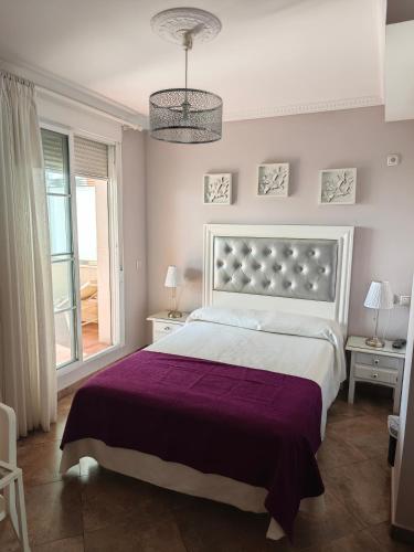 a bedroom with a large bed with a purple blanket at Hotel Miraya Beach in Torre del Mar