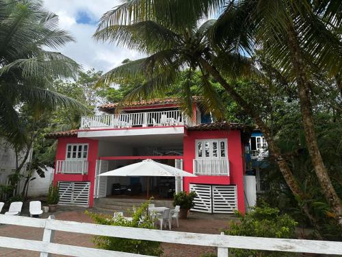 a red and white building with a palm tree at Hotel Miramar Capurganá Casa de playa in Capurganá
