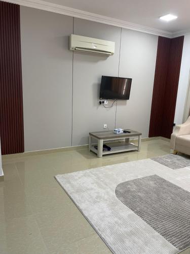 a living room with a tv and a table at شقق مفروشة in ‘Awqad Bayt Marhūn