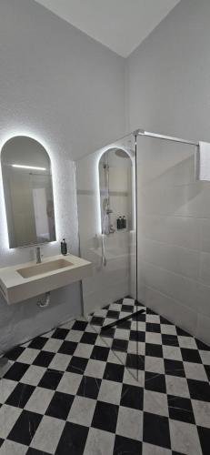 ein Badezimmer mit Waschbecken, Spiegel und Schachbrettboden in der Unterkunft Marchanta Riverside Hotel in Santarém