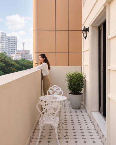 a woman standing on a balcony with a table at Grandala Suites - A Boutique Hotel in Cochin