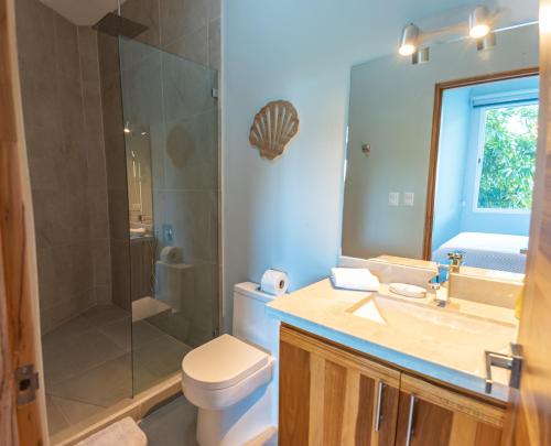 a bathroom with a toilet and a shower and a sink at Villa Costa Vida Tower Suites in Quepos