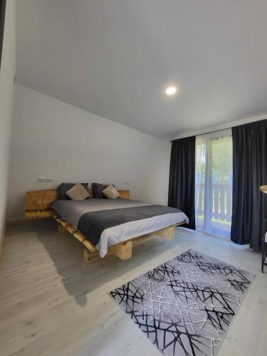 a bedroom with a bed and a large window at Cabana Andi in Brebu