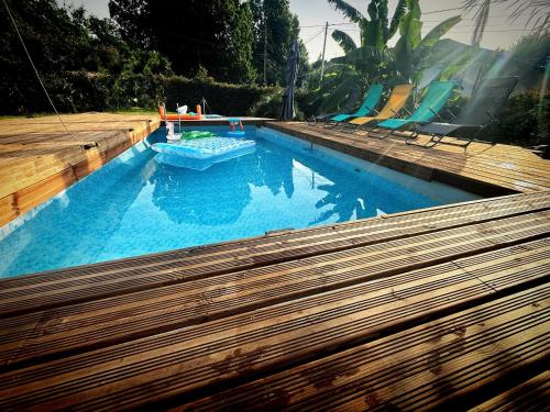 a large swimming pool with a wooden deck and a swimming pool at La Clef des Ondes in Magescq