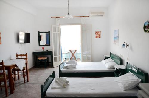a room with two beds and a table and a chair at Litsas Studios Kythnos in Kithnos